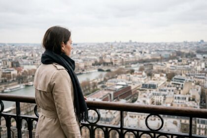 Femme observant le panorama de Paris depuis le deuxième étage de la Tour Eiffel avec vue sur les toits haussmanniens
